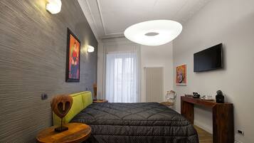 Een moderne slaapkamer met een groot bed, een nachtkastje, een stoel, een televisie en een radiator.