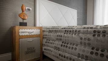 Un dormitorio con cama, mesita de noche y una maleta antigua, e interruptor de luz en la pared.