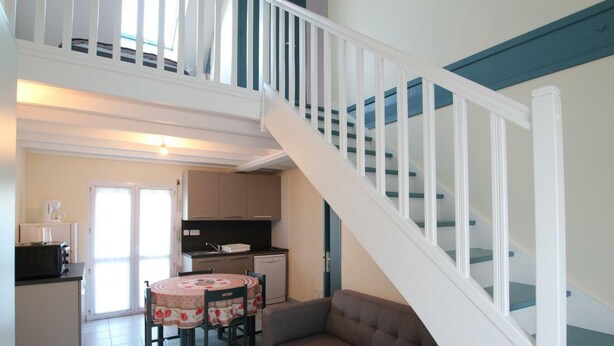 Un grand espace de vie comprenant un escalier, une table à manger avec des chaises et un canapé.