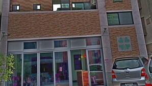 Un immeuble  à étages doté d’une architecture moderne, avec une entrée imposante caractérisée par des portes en verre et une voiture visible, garée devant.