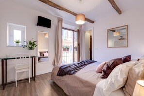 A bedroom with a bed, a desk, a chair, a TV, a mirror, and a window with curtains. - Domus De' Fiori (Rome)