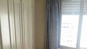 A bedroom with a wooden floor, a single bed, a chair, and a wardrobe. - Gascon MDQ by BonRent (Mar del Plata)