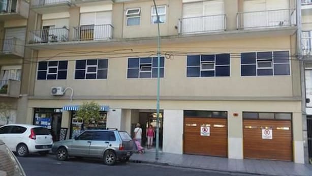 A multi-story building with a flat facade, several windows, and a ground-level entrance with a sign. - Gascon MDQ by BonRent (Mar del Plata)