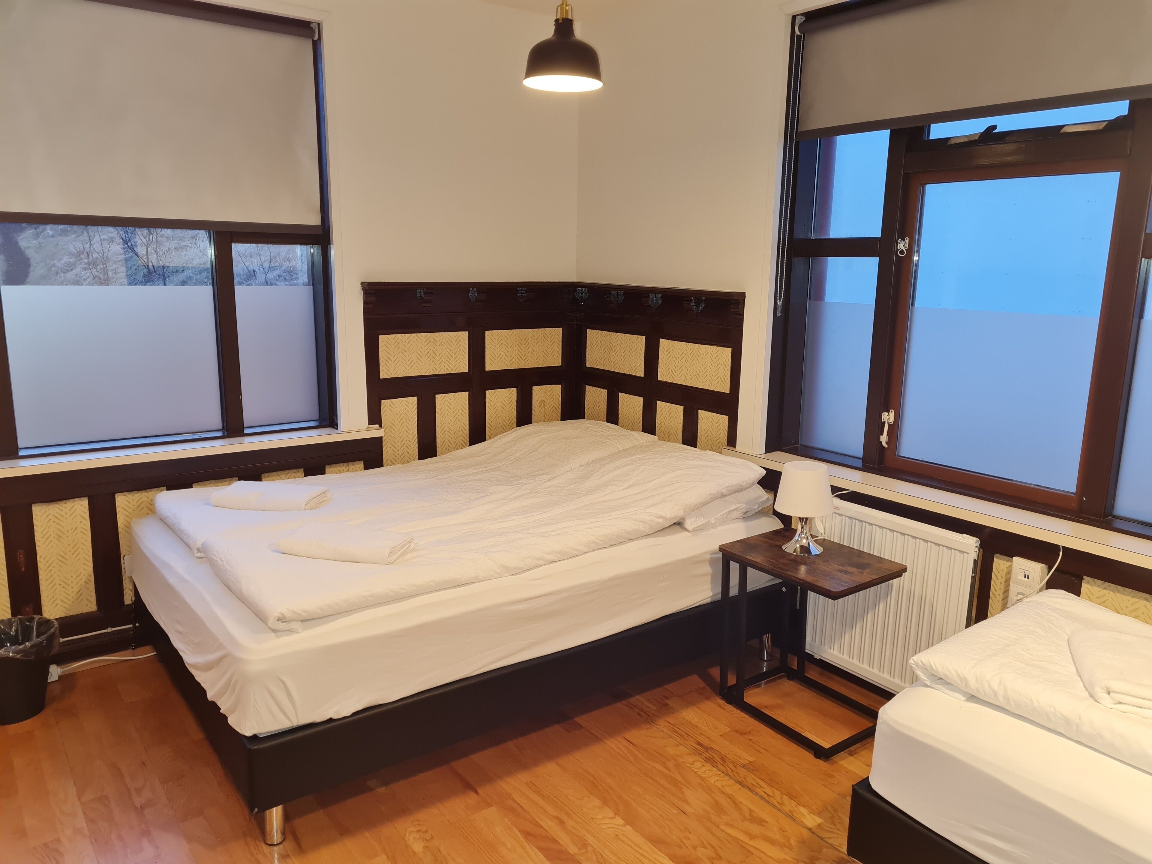 Un dormitorio con una cama, una mesita de noche, una lámpara y una ventana.