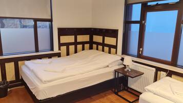 Un dormitorio con una cama, una mesita de noche, una lámpara y una ventana.