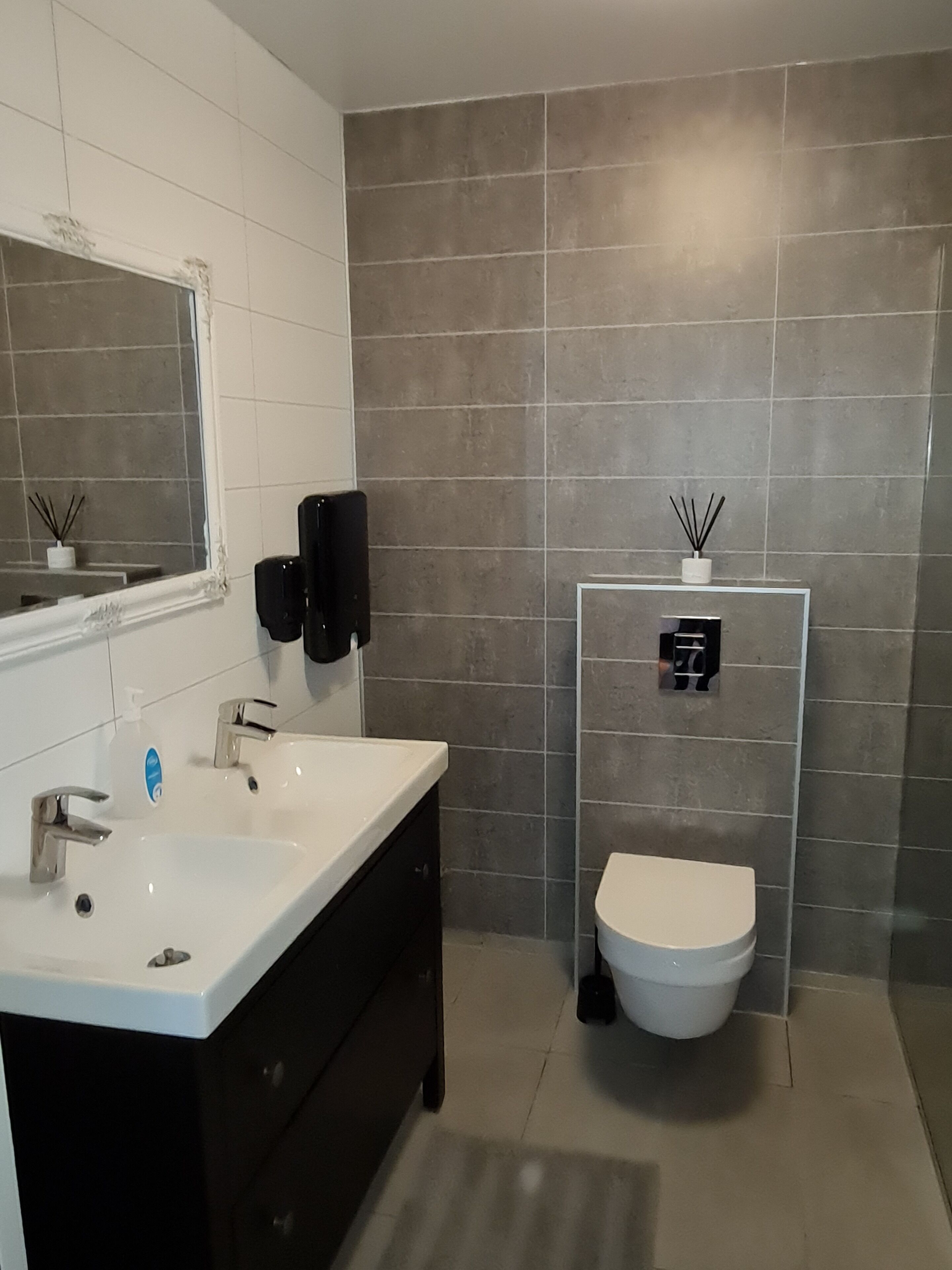 A modern bathroom with a white sink, black cabinet, and a toilet.