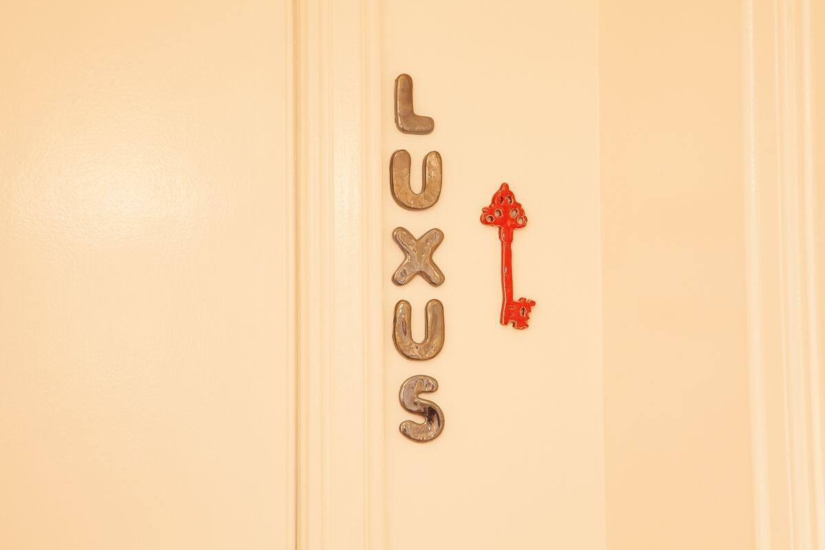 Una puerta con la palabra "LUXUS" escrita en letras metálicas y un adorno en forma de llave roja.