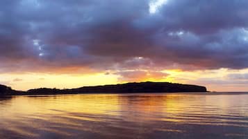 A sunset over a calm body of water with a distant landmass.