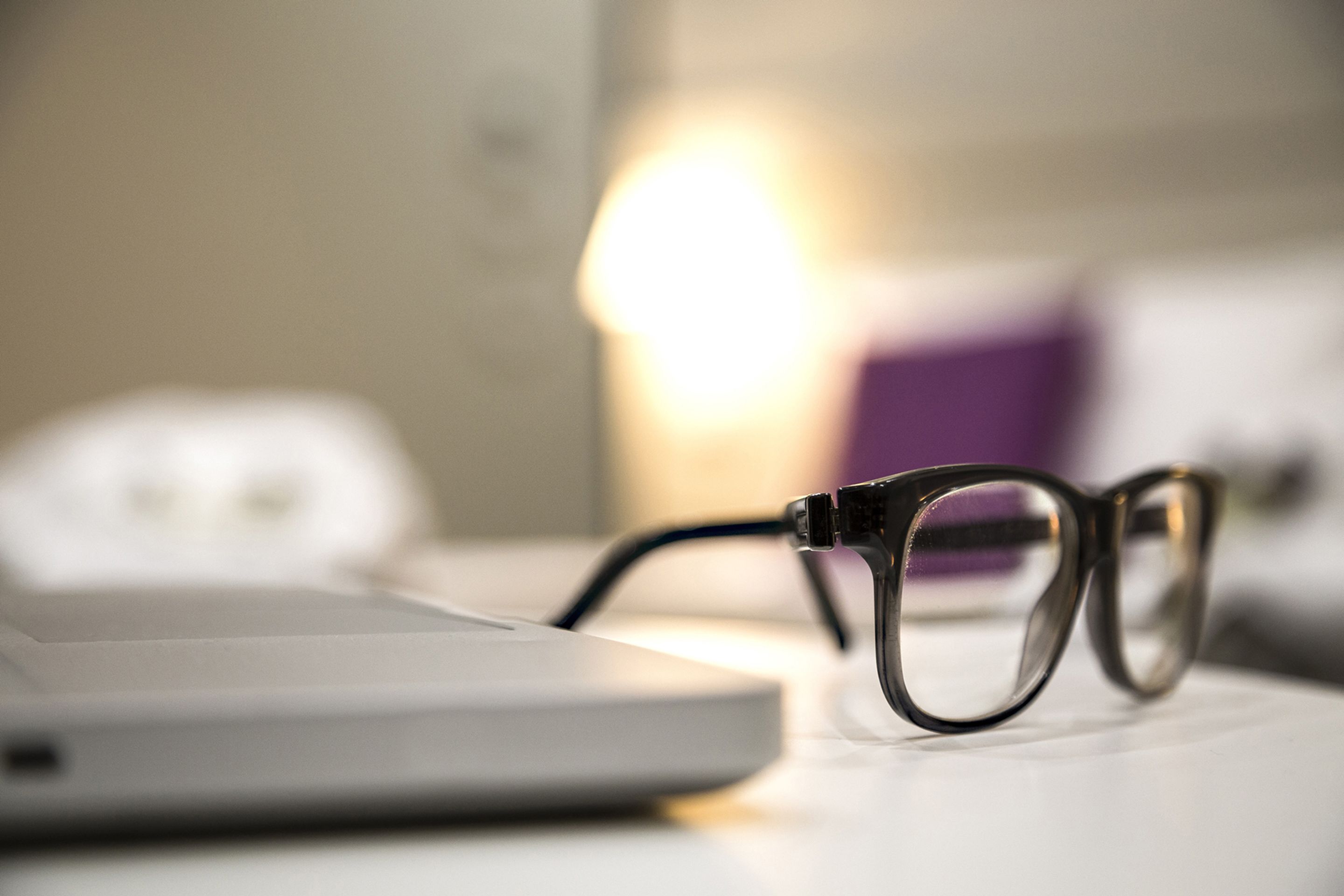 Un par de gafas sobre una superficie blanca con fondo desenfocado.