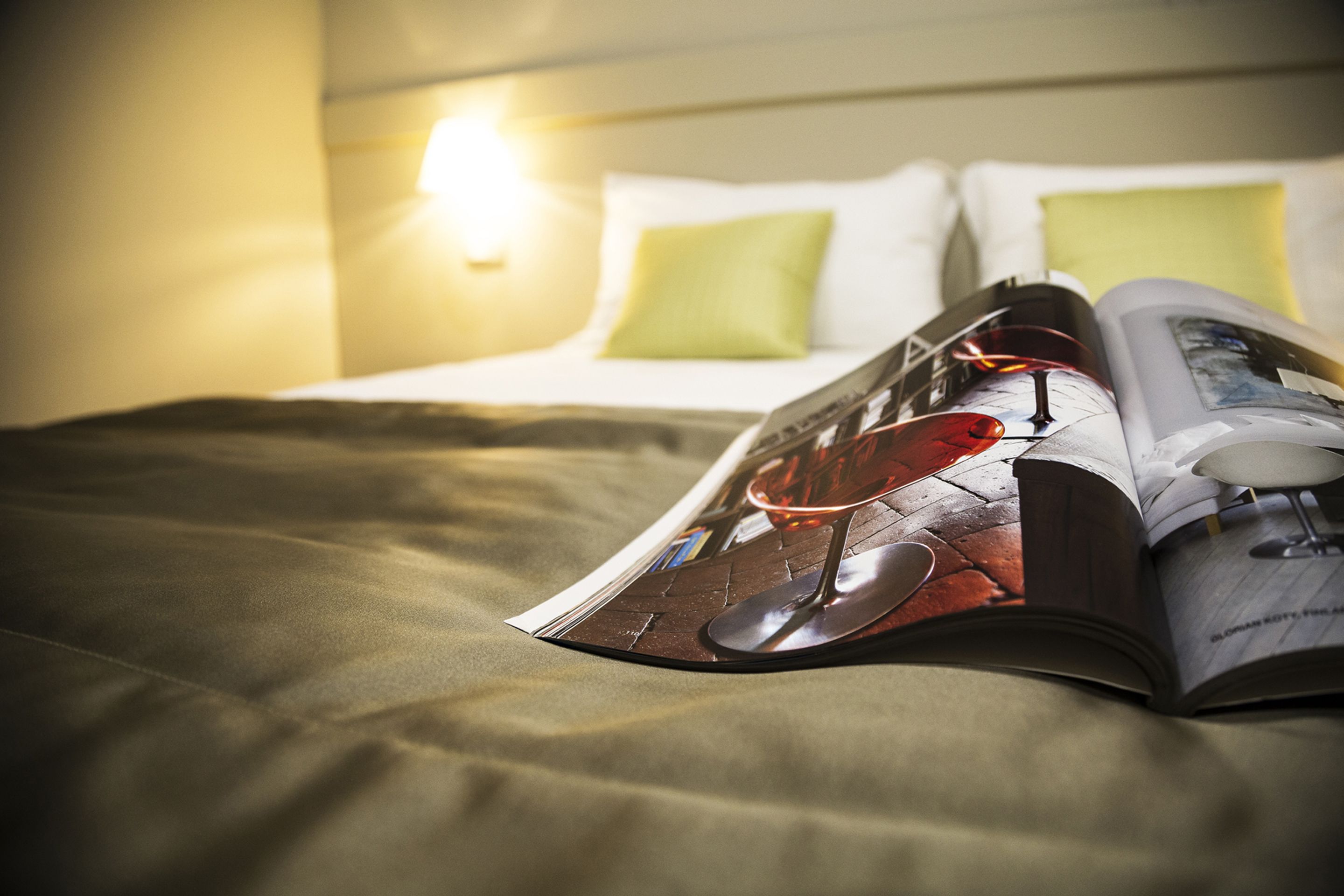 Una revista sobre la cama, junto a un almohadón y una manta.