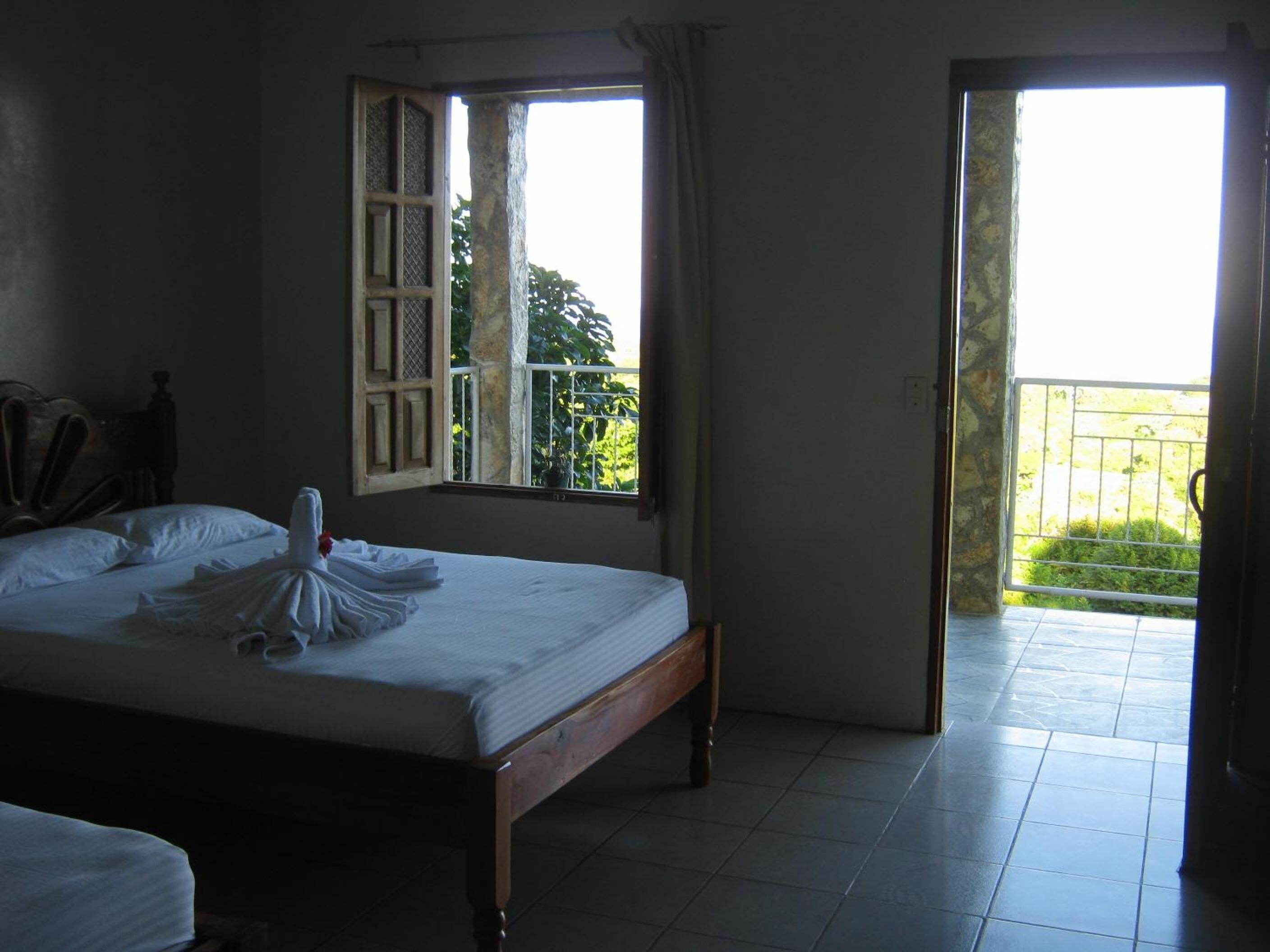 Un dormitorio con cama, ventana y vistas a zonas verdes.