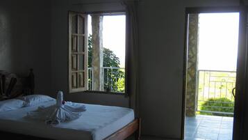 Un dormitorio con cama, ventana y vistas a zonas verdes.