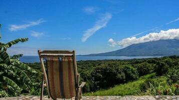 A chair facing a scenic view of a mountain and a body of water.
