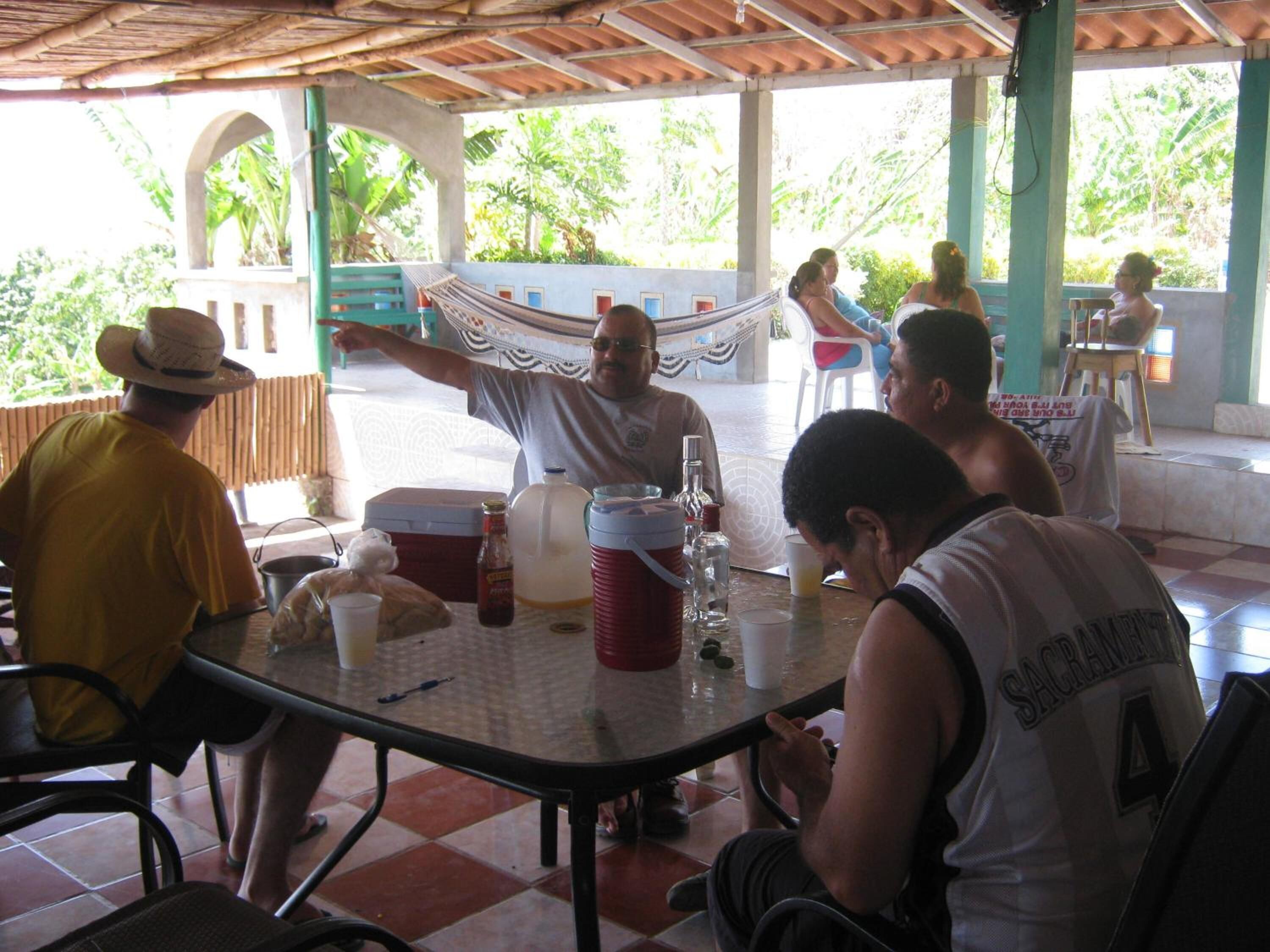A covered outdoor dining area with a table, chairs, and a hammock.