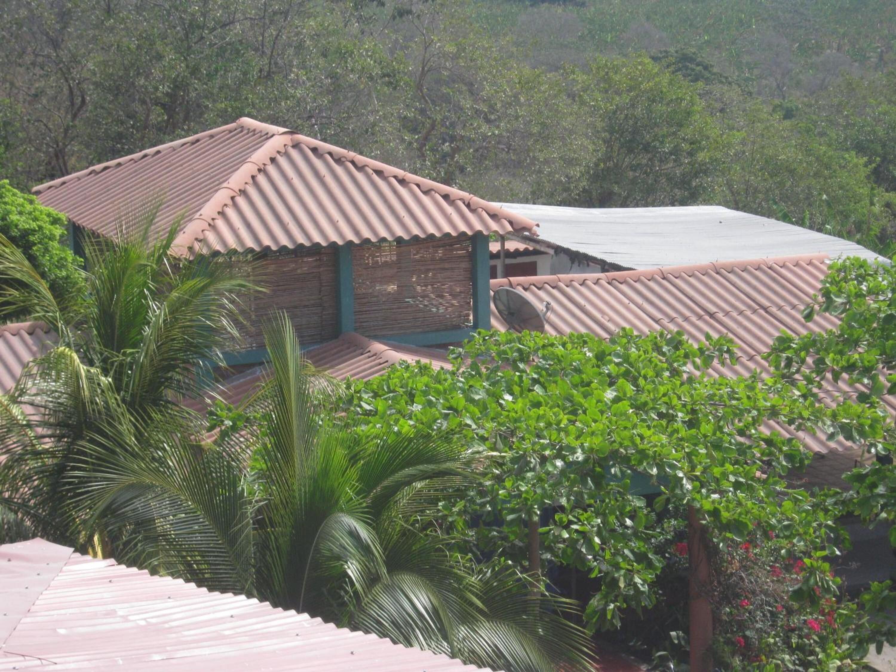 A building with corrugated metal roofs and a satellite dish, surrounded by lush greenery.