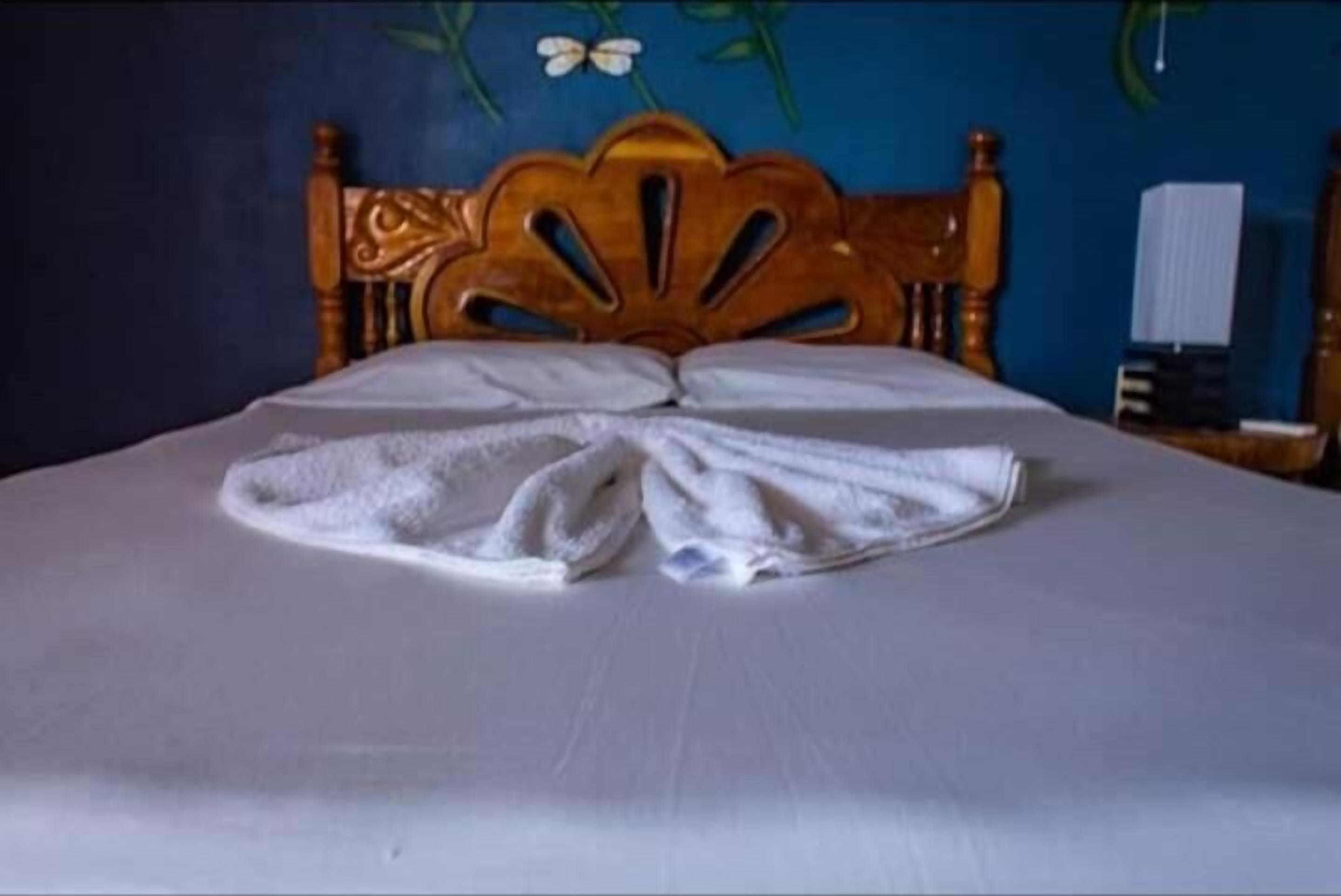 Una cama con cabecera de madera y colcha blanca.