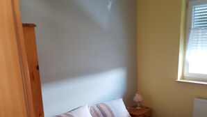 A single bed with a wooden headboard, a bedside table with a lamp, and a window with blinds. - Albergo Restaurante Da Franco (Buechenbeuren)