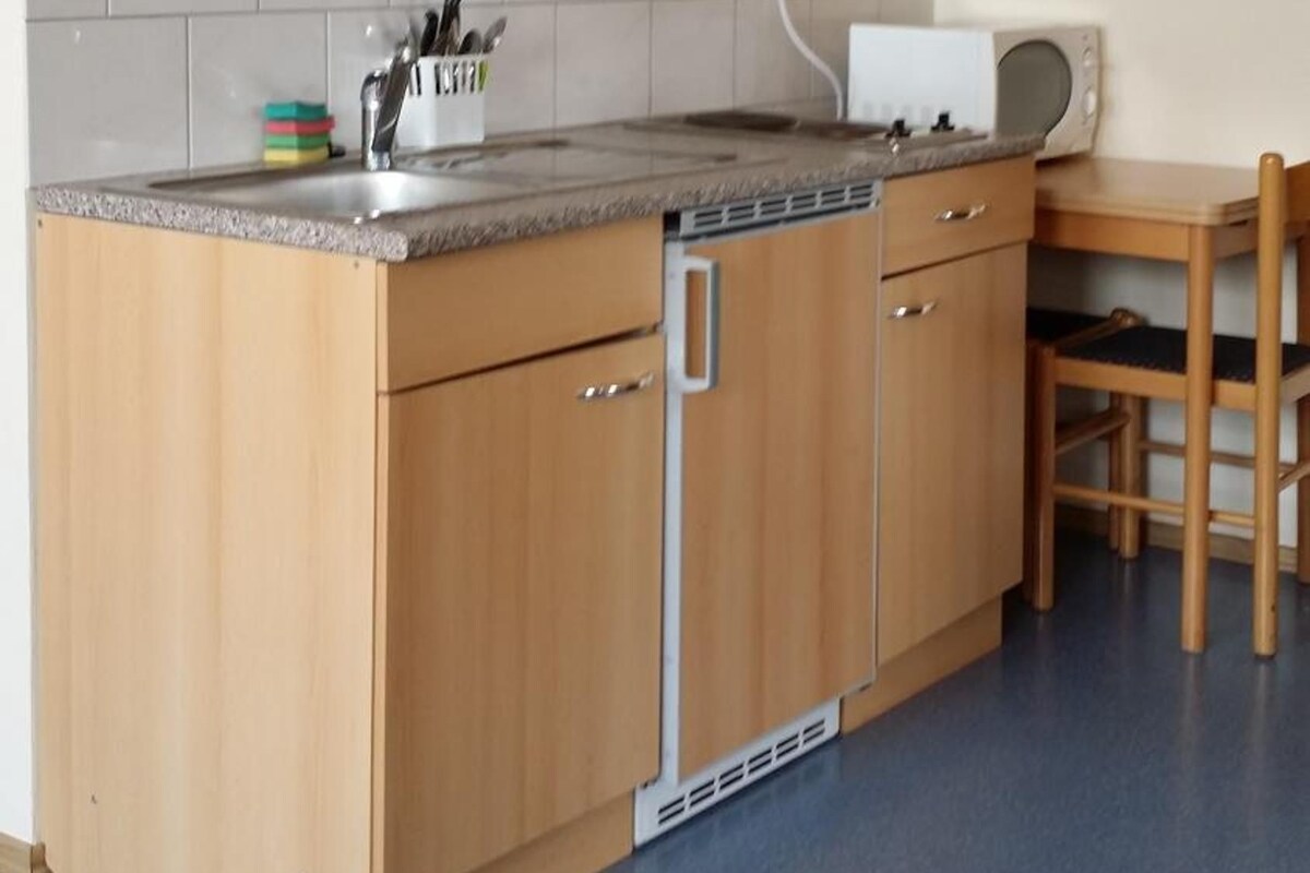 A kitchen with wooden cabinets, a built-in dishwasher, a countertop with a sink, and a dining area with a table and chairs.