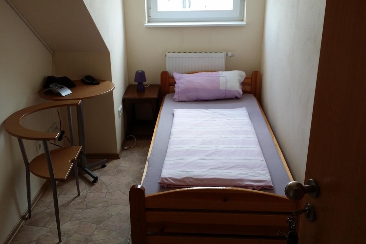 A small room with a bed, a desk, and a chair.