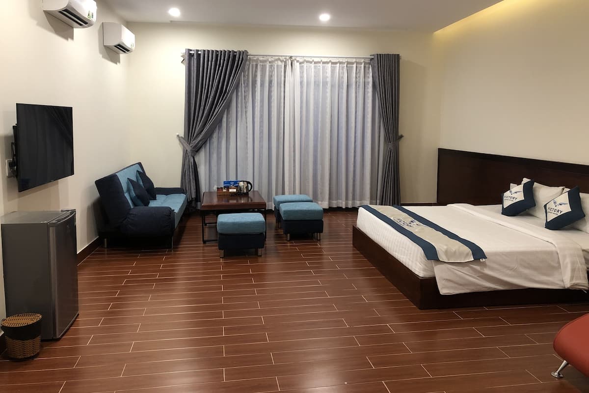A hotel room with a bed, a sofa, a small table, and a TV.