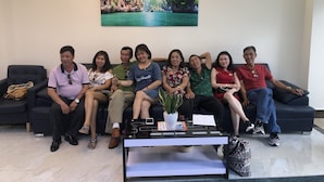 A group of people seated on a dark-colored sofa in a room with a large painting of a waterfall and greenery on the wall. - Victory Airport Hotel (Ho Chi Minh City)