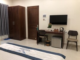 Une chambre d’hôtel comprenant un lit, un bureau avec une chaise, une télévision et un petit réfrigérateur.