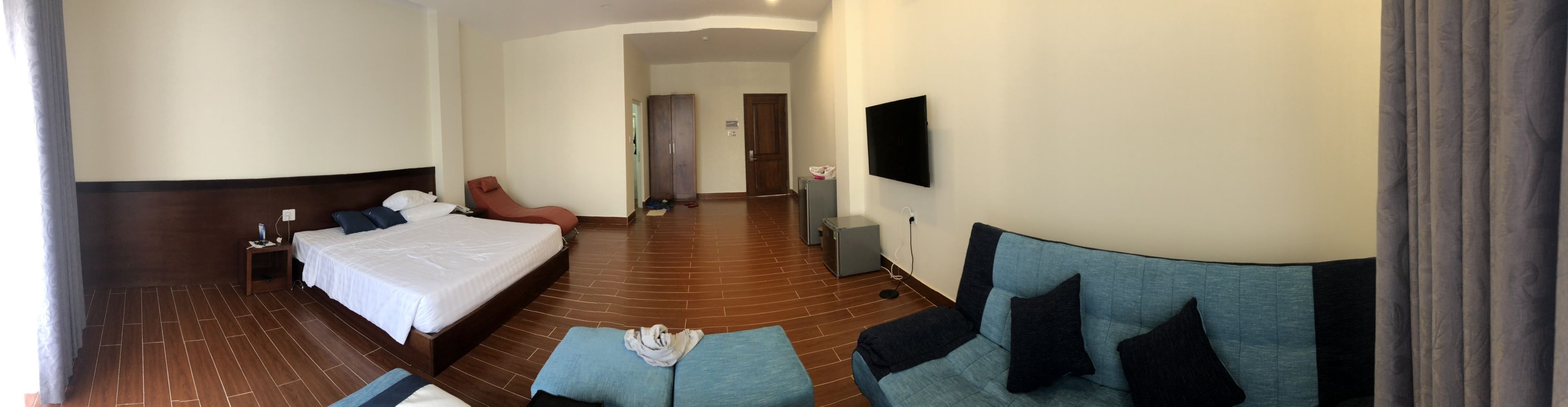 A hotel room with a large bed, a sofa, a TV, and a small table.