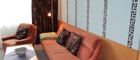 Una habitación acogedora con un sofá, un sillón y una mesita con un cuenco.