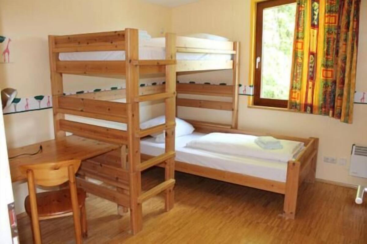 Une chambre avec un lit superposé, un bureau et une chaise.