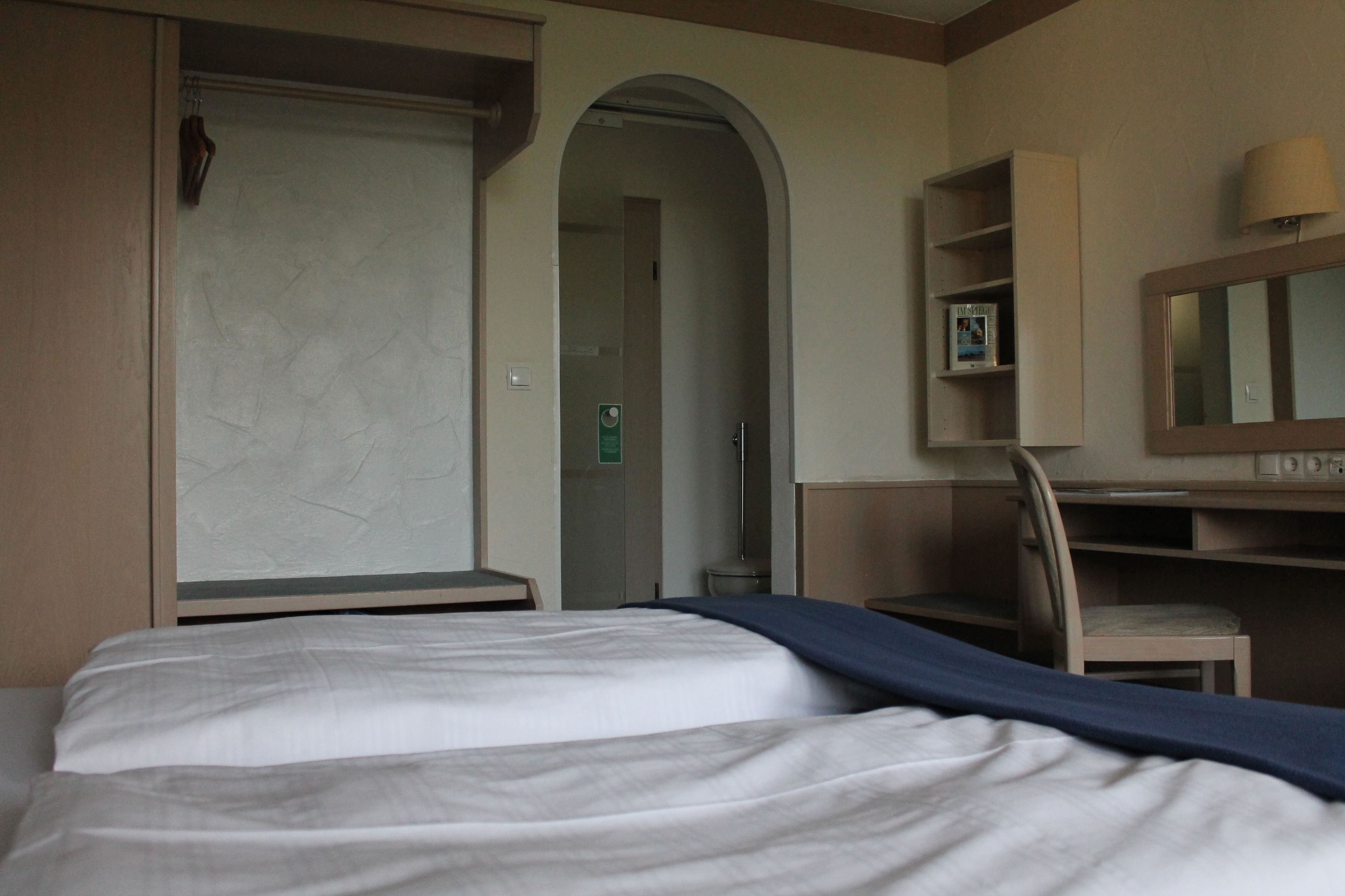 Una habitación de hotel con una cama, un escritorio, una silla y un armario.