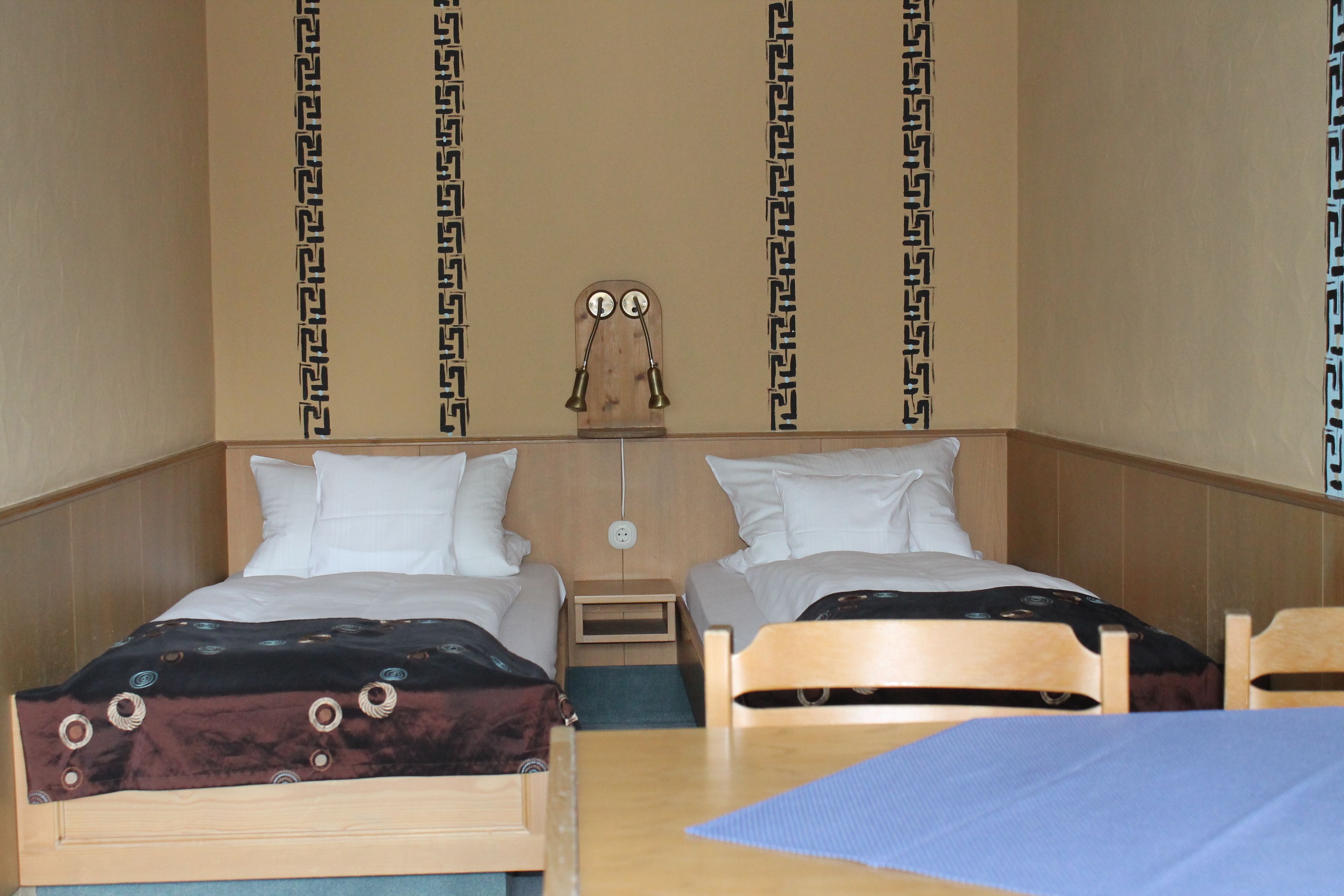 Una habitación de hotel con dos camas, un cabecero de madera, una mesita de noche y un reloj de pared.