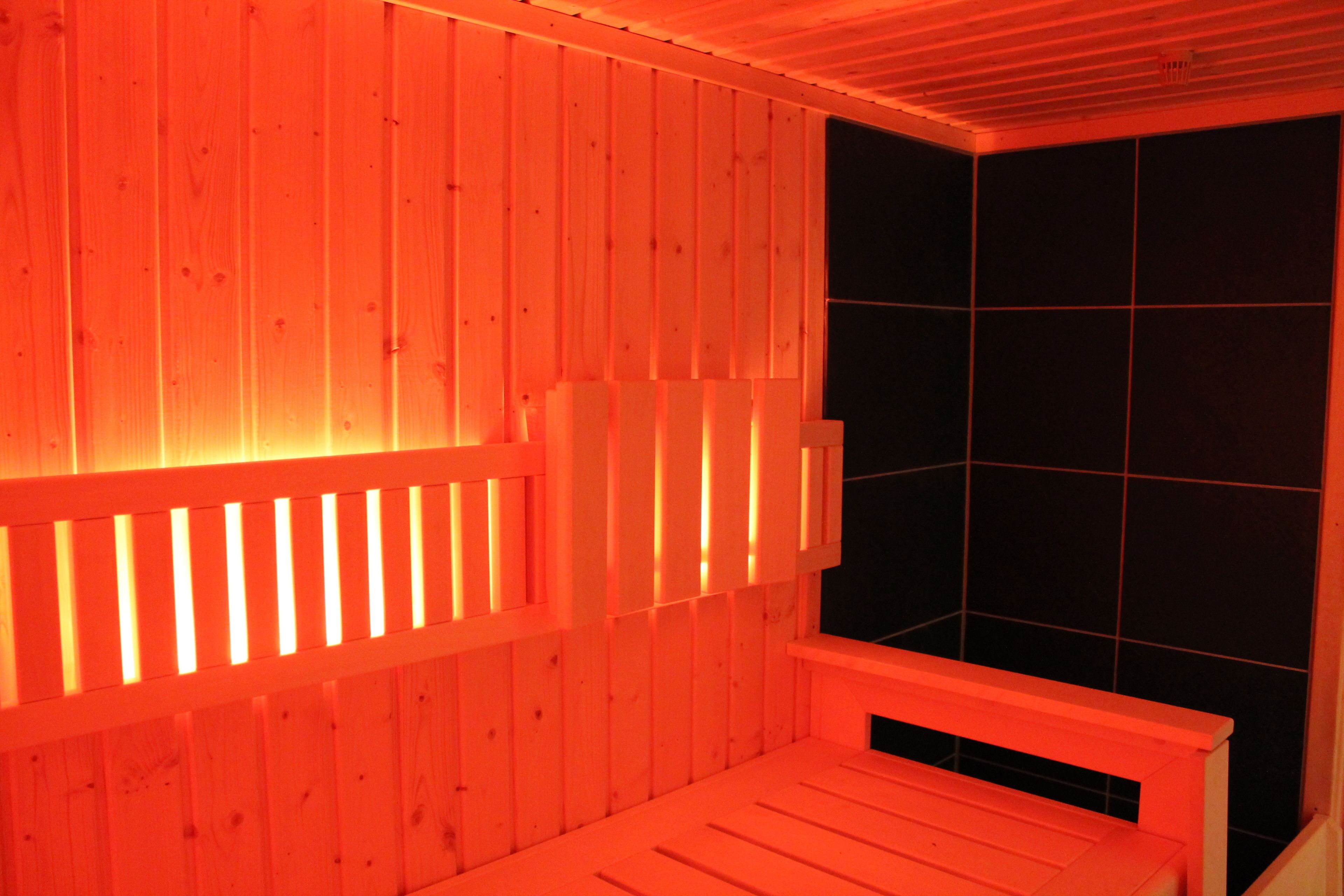 Sauna de fusta amb un banc i una paret revestida de rajoles.
