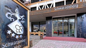 Das Schwarzerberg Hotel mit einem gut sichtbaren Logo, einem roten Teppich und einem von Ziegelsteinen gepflasterten Vorbereich.