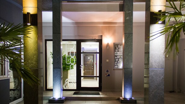 A hotel entrance with a glass door, a reception desk, and a wall-mounted sign. - Hotel Rodon (Katerini)