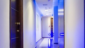 A hotel corridor with a tiled floor, doors, and a blue-lit wall. - Hotel Rodon (Katerini)