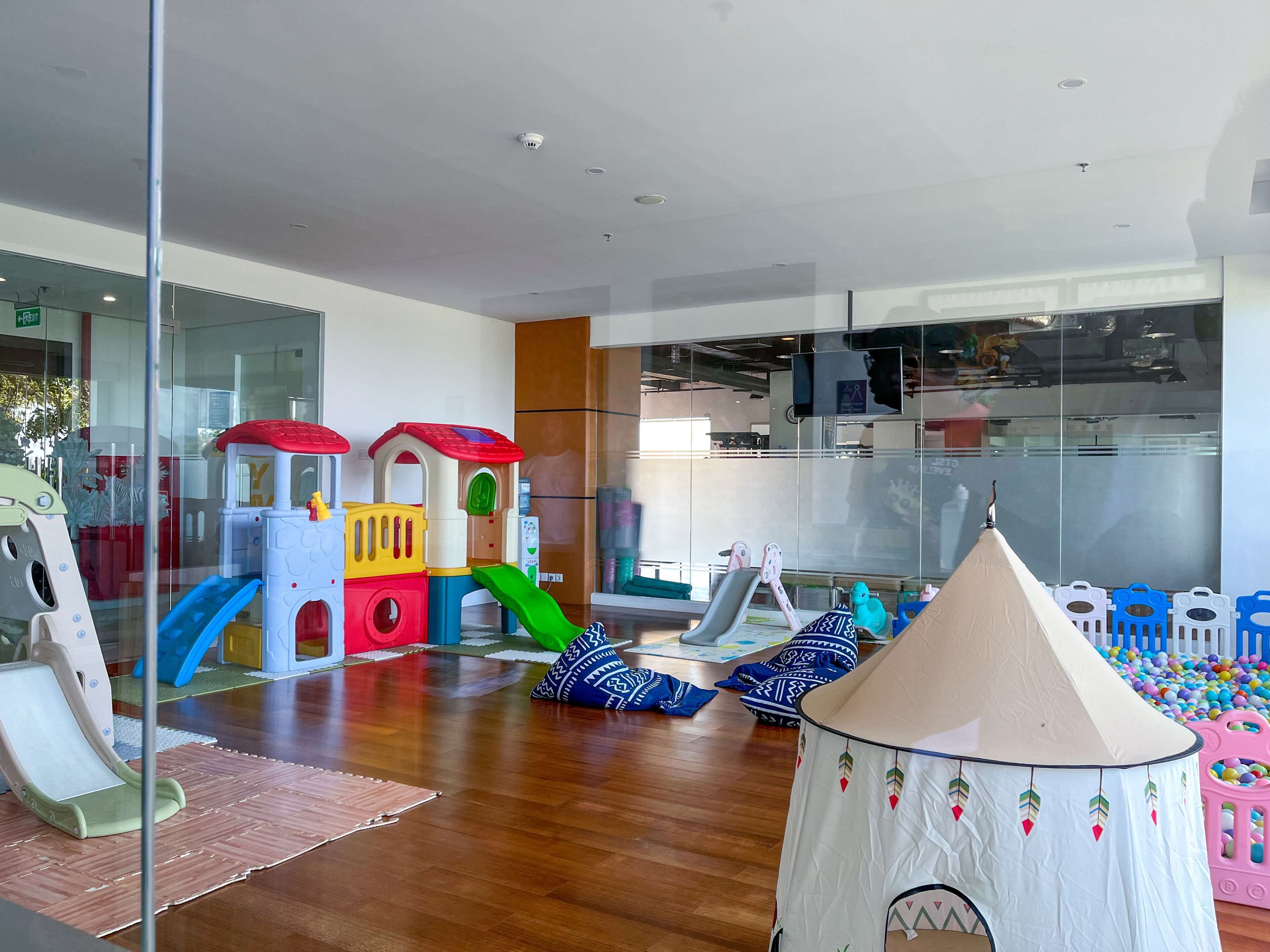 Espaço de recreação com escorrega, estruturas de escalada e uma tenda.