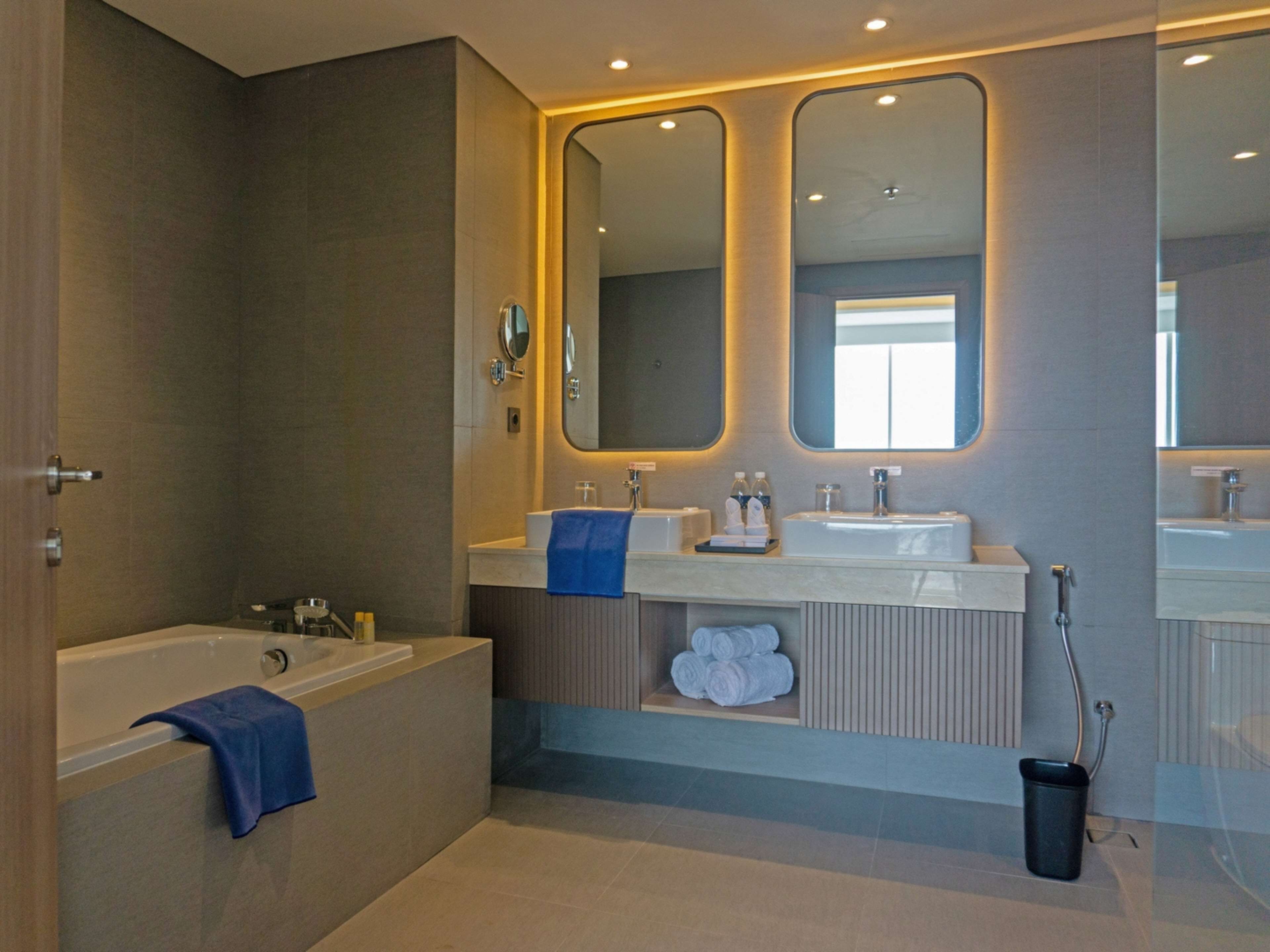 Une salle de bain moderne avec une baignoire, deux lavabos et un grand miroir.