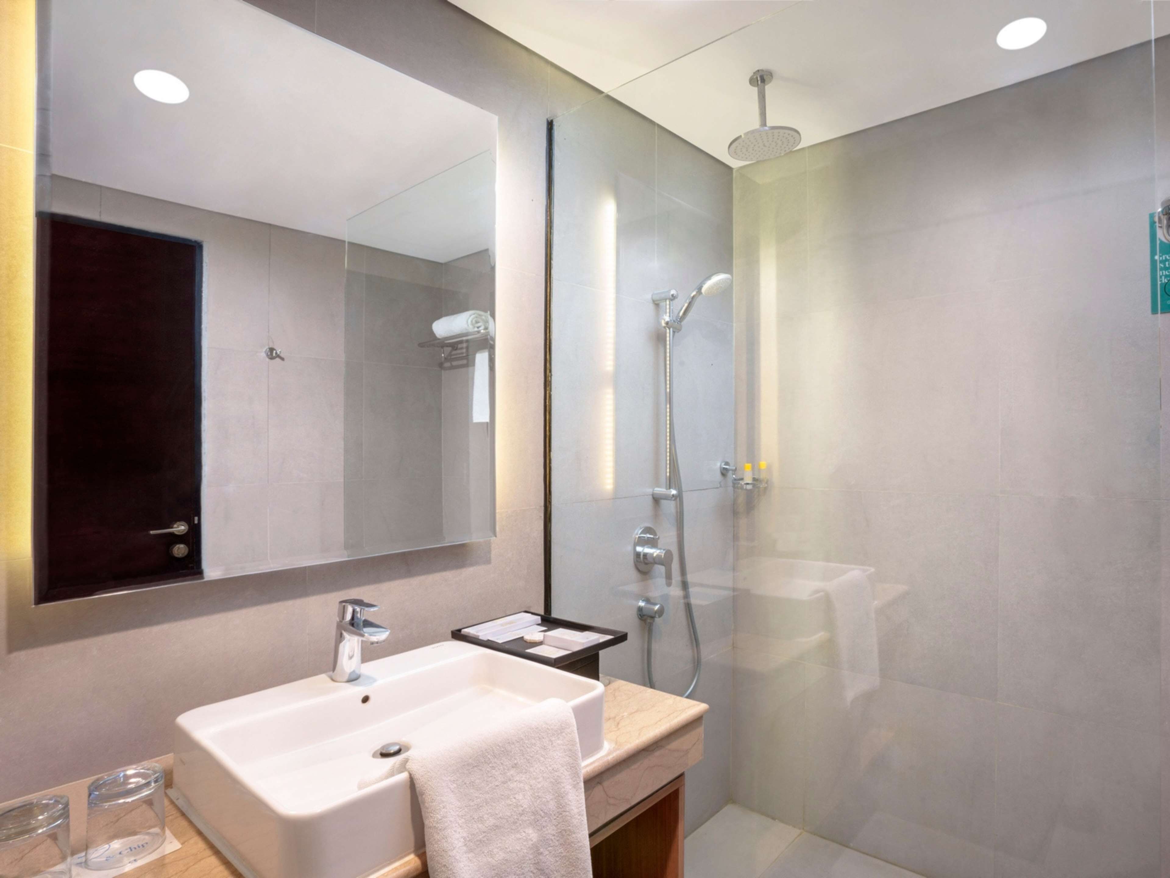 Un baño moderno con un espejo grande, un lavabo y una zona de ducha.