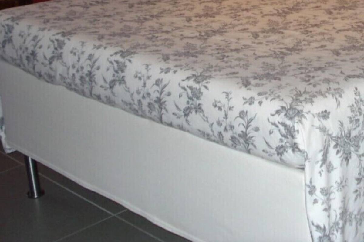 A bed with a floral bedspread, a white lamp, and a wooden nightstand with a bowl.