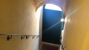 Una escalera con barandilla, una puerta oscura en la parte superior y una fuente de luz encima de la puerta.