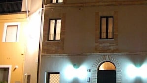 Un edificio de varios pisos con una entrada central en arco, ventanas iluminadas y fachada de piedra.