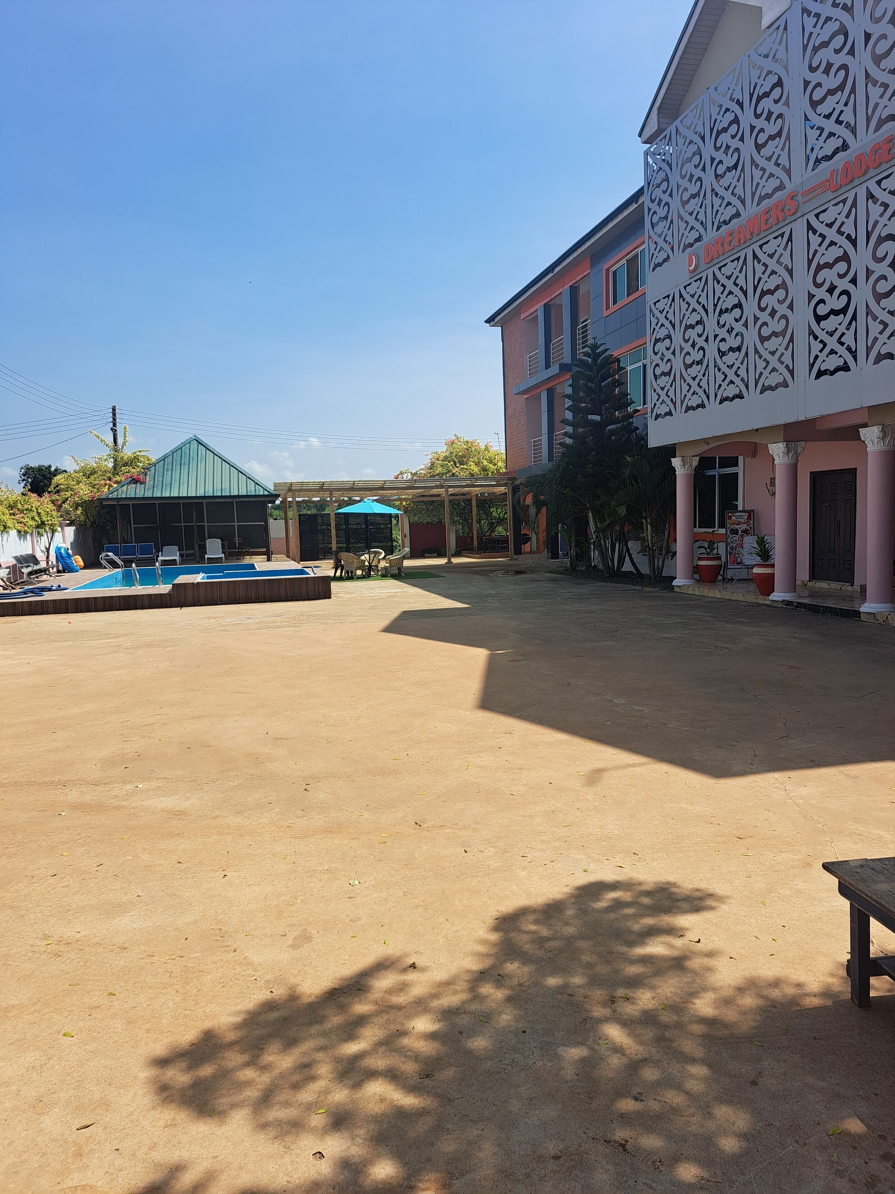 Un pati amb una piscina, mobiliari exterior i un edifici amb façana decorada.