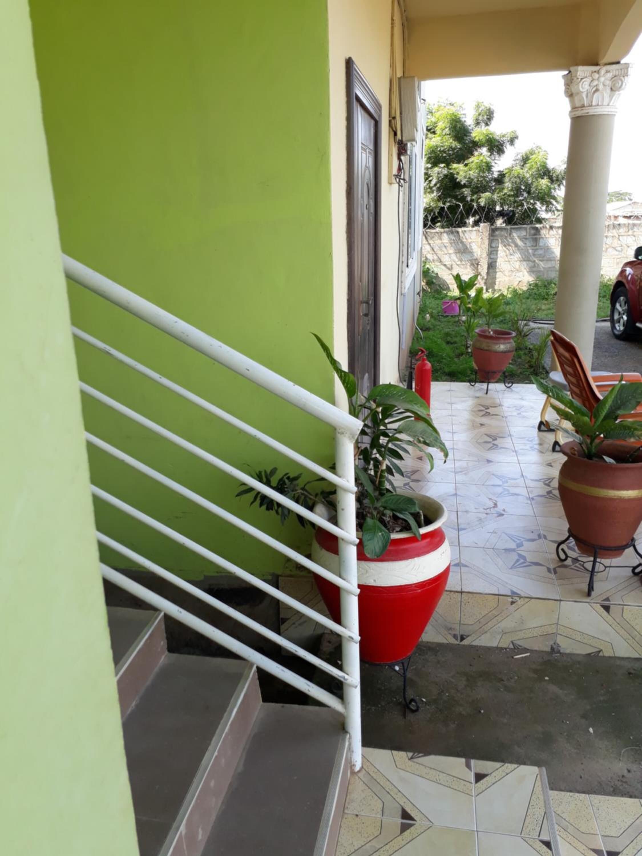 A staircase with white railings leading to a covered area with potted plants and a red fire extinguisher.