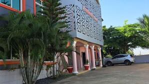 A modern building with a distinctive facade, large windows, and a parking area with a car. - Dreamers Lodge (Prampram)