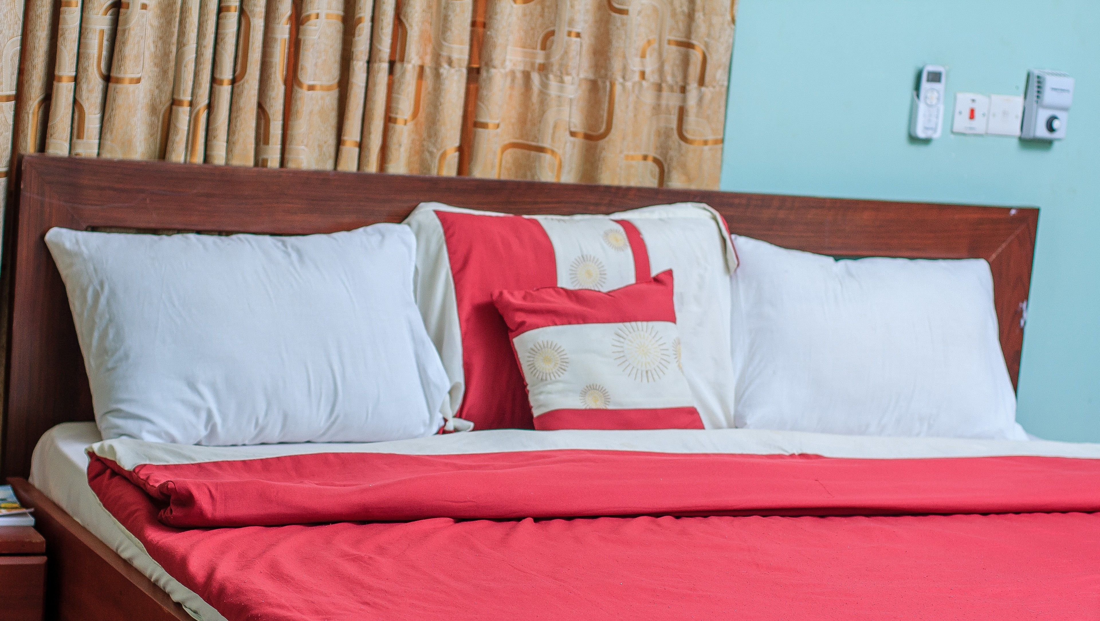 A bed with a wooden headboard, white and red bedding, and a red blanket.