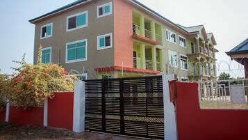A multi-story residential building with a gated entrance, balconies, and a small garden area.