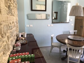 A dining area with a wooden table, white chairs, a mirror, and a lamp.