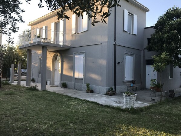A two-story house with a balcony, a garage, and a small garden area with potted plants.