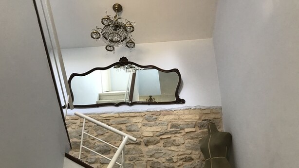 Un escalier avec un mur en pierre, un miroir et un lustre.
