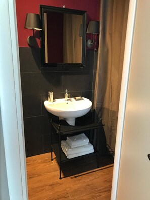 A bathroom with a white sink, two wall-mounted lamps, and a mirror.